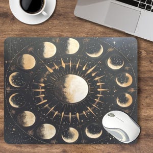 Pode incluir: Um tapete de rato preto com um design de fases lunares em ouro e branco. O design apresenta um círculo de luas em diferentes fases, com um sol no centro. O tapete de rato é perfeito para adicionar um toque de estilo celestial à sua secretária.