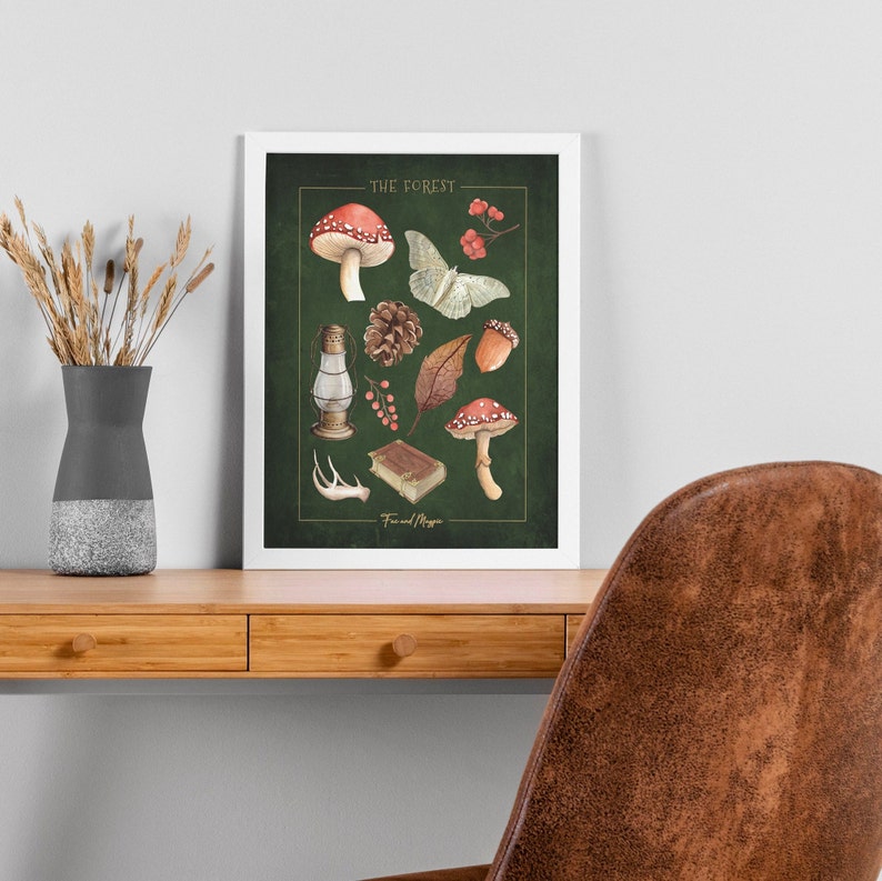 May include: A framed print with a green background featuring illustrations of forest elements, including mushrooms, a moth, a pine cone, leaves, berries, a lantern, a book, and antlers. The text "THE FOREST" and "Fire and Magic" are included in the print.
