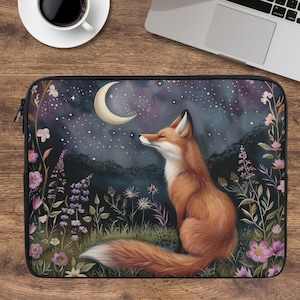 May include: A laptop sleeve with a design of a fox looking at a crescent moon under a starry night sky. The design includes wildflowers in pink, purple, and white, set against a dark blue and green background.