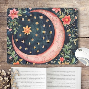 Può includere: Una falce di luna rosa con un contorno dorato e un motivo floreale su uno sfondo blu scuro con stelle dorate. La luna è circondata da viti verdi e fiori rosa.