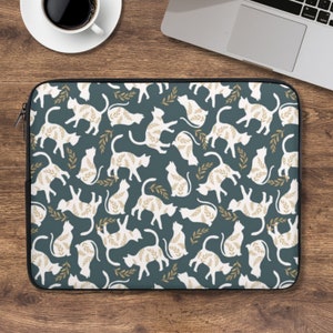 Può includere: Una custodia per laptop blu turchese con un motivo a silhouette bianca di gatti e ramoscelli dorati.