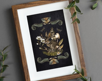 Puede incluir: Una impresión enmarcada con un fondo oscuro que presenta una ilustración estilizada de un conejo en un entorno de bosque. El conejo está rodeado de helechos, setas y flores. La impresión está enmarcada en un marco de madera oscura.