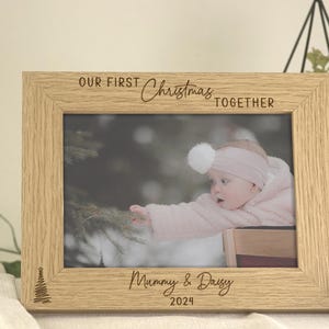 Pu&ograve; includere: Una cornice per foto in legno con il testo "Our First Christmas Together" e "Mommy & Daddy 2024". La cornice contiene una foto di una bambina vestita di rosa.