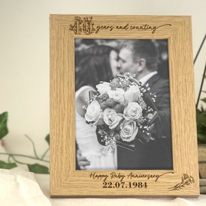 May include: A wooden photo frame with a black and white photo of a couple holding a bouquet of flowers. The frame is engraved with "40 years and counting", "Happy Ruby Anniversary", and the date 22.07.1984.