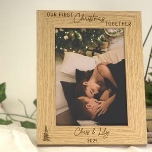 May include: A wooden photo frame with the text "Our First Christmas Together" and "Chris & Lily 2024" engraved on it. The frame has a picture of a couple cuddling on a bed.