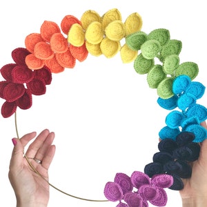 May include: A rainbow crochet wreath made of individual crocheted flower shapes in red, orange, yellow, green, blue, purple, and pink.