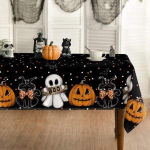 May include: A black rectangular tablecloth featuring a repeating Halloween pattern of orange jack-o'-lanterns, white ghosts holding a sign that says BOO, and black cats wearing orange and white polka-dot bow ties, accented with white and orange dots.