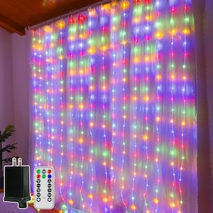 May include: A curtain of vertical LED string lights featuring multicolored bulbs in red, green, blue, and yellow. The light set includes a black power adapter plug and a rectangular remote control with multiple buttons for color and mode settings.