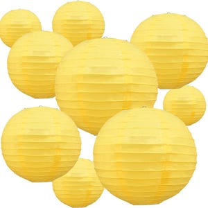 May include: A collection of yellow paper lanterns, spherical in shape, with horizontal ribbed detailing. The lanterns are of varying sizes and are arranged against a white background. These decorative lanterns are suitable for parties and events.
