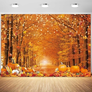May include: A photography backdrop featuring a forest path lined with tall trees covered in vibrant orange and yellow autumn leaves, illuminated by hanging string lights, with a collection of orange pumpkins scattered across the foreground.
