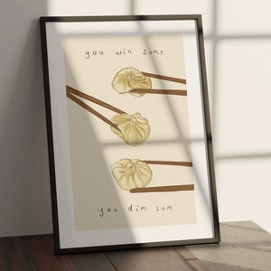 Może przedstawiać: Wydruk w ramie z jasnobeżowym tłem przedstawiający ręcznie rysowaną ilustrację trzech gotowanych na parze bułeczek z pałeczkami. Tekst "you win some you dim sum" jest napisany czarnym kolorem.
