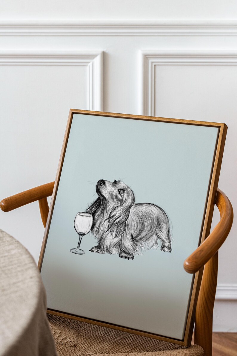 May include: A framed black and white illustration of a dachshund dog holding a wine glass. The dog is looking up and the background is a light blue color.