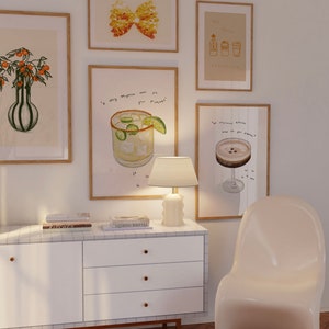 May include: A white dresser with four drawers and gold handles. The dresser is decorated with white tiles. Above the dresser are eight framed illustrations, including a butterfly, a margarita, a cocktail, and a bottle of liquor. The dresser is in front of a white wall and a light wood floor.