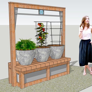 May include: A wooden planter with three large grey pots, two with plants and one with a tomato plant growing on a trellis. The planter has a bench and a shelf.
