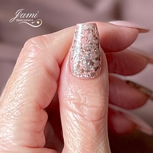 May include: Close-up of a finger with a pink and silver glitter nail polish. The nail is long and oval shaped.