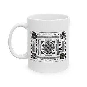 May include: White ceramic mug with a black and white test pattern printed on the front. The pattern includes numbers, letters, circles, and lines.