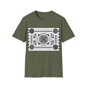 May include: Olive green t-shirt featuring a black and white graphic print. The graphic resembles a test pattern with concentric circles, lines, and the numbers 1-9 and letters A-I. The shirt has short sleeves and a crew neck.