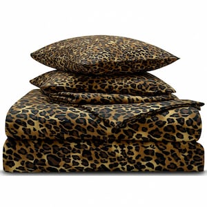 May include: A bedding set featuring a bold leopard print pattern in shades of brown, tan, and black. The set includes a folded flat sheet, a fitted sheet, and two matching pillowcases stacked neatly on top of the folded bedding layers.