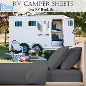 May include: Gray RV camper sheets for bunk beds. The sheets are on a bed with two pillows. The RV is in the background. The RV has a white exterior with a black heart logo that says "LS" and "LUCK SHREE".