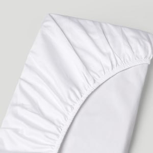 May include: A white fitted sheet with elasticized edges, partially folded. The sheet is made of a smooth, wrinkle-resistant fabric. The overall theme is bedding and home textiles.