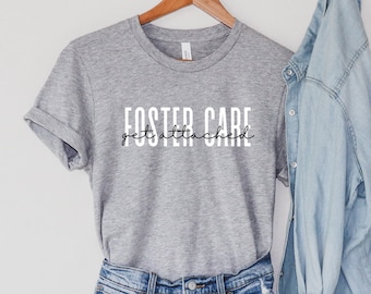 May include: Gray t-shirt with the text "Foster Care get attached" in black lettering.