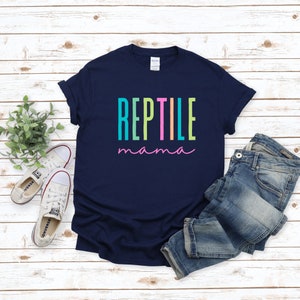May include: A navy blue t-shirt with the text "REPTILE mama" in rainbow colors. The text is in a vertical stacked format with each letter in a different color.