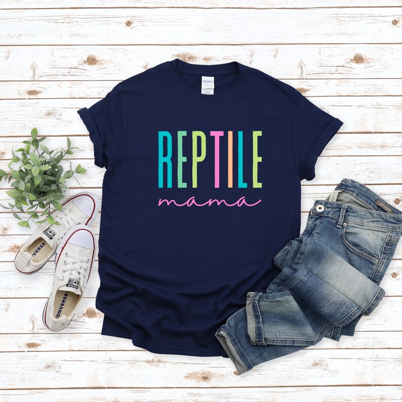 May include: A navy blue t-shirt with the text "REPTILE mama" in rainbow colors. The text is in a vertical stacked format with each letter in a different color.