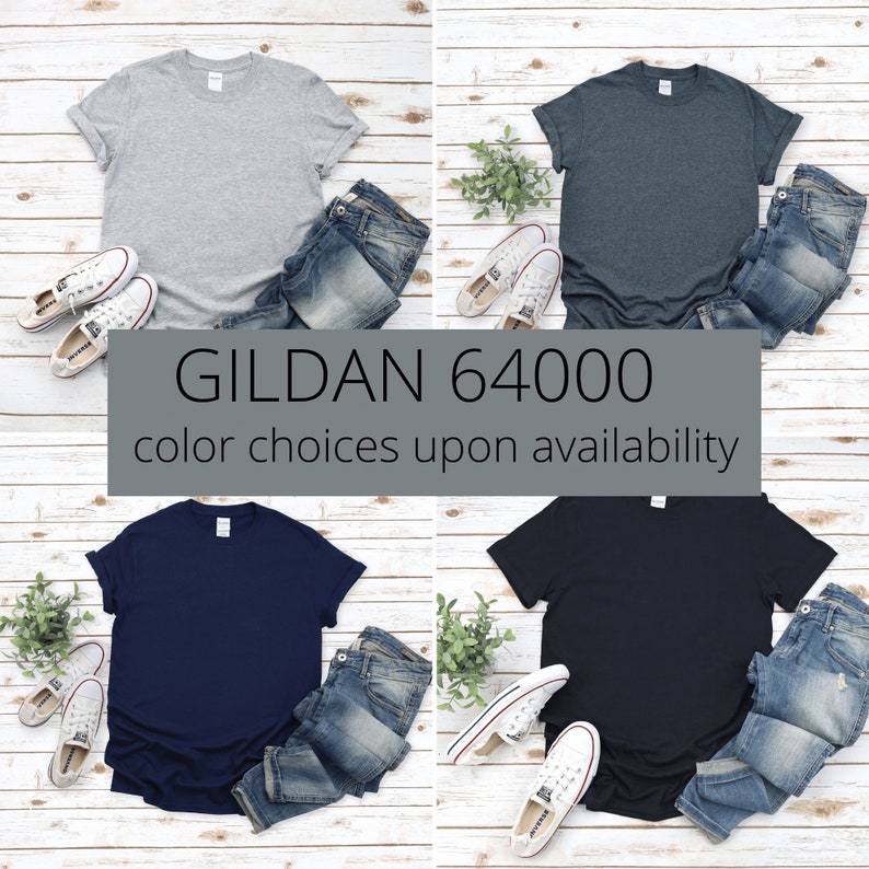 Op de afbeelding: Vier effen T-shirts in verschillende kleuren: grijs, donkerblauw, marineblauw en zwart. De T-shirts liggen op een witte houten achtergrond met jeans en sneakers. De tekst "GILDAN 64000" en "kleurkeuze afhankelijk van beschikbaarheid" staat onder de shirts.