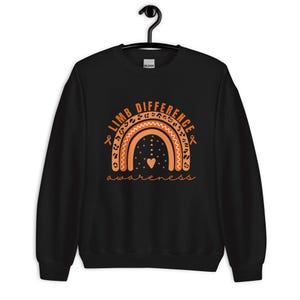 Peut inclure: Sweat-shirt noir avec un motif arc-en-ciel orange et le texte "Limb Difference Awareness" en orange.