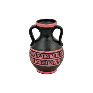 Könnte beinhalten: Kleine, schwarze Vase mit zwei Henkeln und einem rosa Rand und Boden. Die Vase hat ein sich wiederholendes rosa griechisches Schlüsselmuster um ihren Mittelteil. Das Design erinnert an antike Keramik.