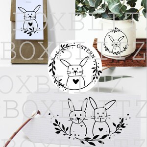 Pode incluir: Um conjunto de tr&ecirc;s carimbos de borracha preto e branco com coelhos com cora&ccedil;&otilde;es e grinaldas florais. Os carimbos s&atilde;o projetados para projetos de artesanato e scrapbooking. Os carimbos s&atilde;o etiquetados com "Ostern", que &eacute; alem&atilde;o para P&aacute;scoa.
