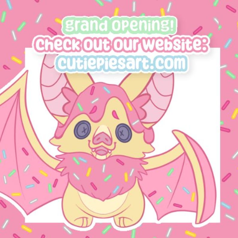 May include: A cartoon bat illustration with a pink and yellow color scheme, decorated with sprinkles. The bat has button eyes and a frosting-like design. Text reads "grand opening! Check out our website: cutiepiesart.com".