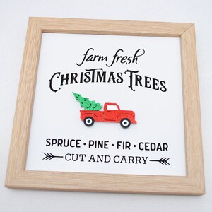 Puede incluir: Un cartel enmarcado con el texto "farm fresh CHRISTMAS TREES" y un cami&oacute;n rojo con un &aacute;rbol de Navidad en la caja. El cartel tambi&eacute;n dice "SPRUCE - PINE - FIR - CEDAR" y "CUT AND CARRY" con flechas.