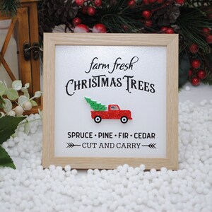 Puede incluir: Un cartel enmarcado con el texto "farm fresh CHRISTMAS TREES" y un cami&oacute;n rojo con un &aacute;rbol de Navidad en la parte trasera. El cartel tambi&eacute;n dice "SPRUCE - PINE - FIR - CEDAR - CUT AND CARRY - "