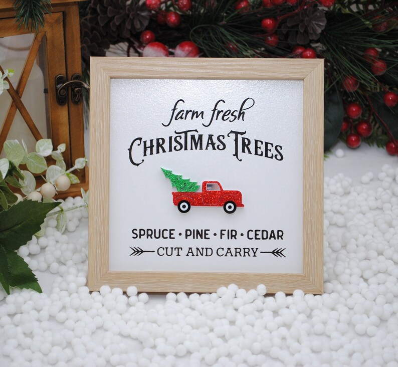 Puede incluir: Un cartel enmarcado con el texto "farm fresh CHRISTMAS TREES" y un cami&oacute;n rojo con un &aacute;rbol de Navidad en la parte trasera. El cartel tambi&eacute;n dice "SPRUCE - PINE - FIR - CEDAR - CUT AND CARRY - "
