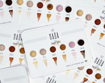 May include: A set of small, round, colorful clay paint samples labeled with the words "Set Hada" and "Donuts Colors". The colors include beige, orange, brown, pink, and white.