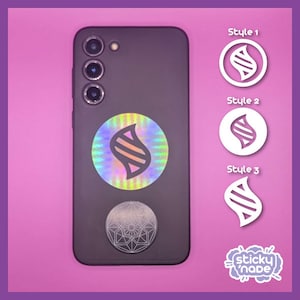 Puede incluir: Una funda de teléfono negra con una pegatina holográfica de una 'S' estilizada con un patrón geométrico. La funda del teléfono tiene una lente de cámara triple. Tres círculos blancos con diferentes estilos de 'S' se muestran en el lado derecho de la imagen. El texto 'Style 1', 'Style 2' y 'Style 3' está encima de cada círculo. El texto 'sticky 'nade' está en una forma de nube blanca en la esquina inferior derecha de la imagen.