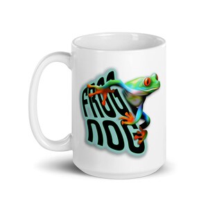 May include: White ceramic mug with a green, blue, and orange frog design. The frog is climbing up the side of the mug. The text "Frog Dog" is printed on the mug in black.