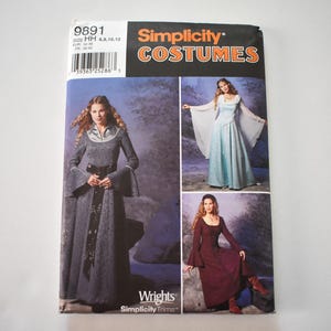 May include: Simplicity Costumes sewing pattern 9891, size HH 6, 8, 10, 12. The envelope features three floor-length dress designs: a grey long-sleeved gown with a black sash, a light blue gown with sheer sleeves, and a dark red long-sleeved gown.
