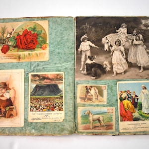 May include: An open antique scrapbook with various vintage illustrations and postcards. The pages are a light teal color. The illustrations include a rose, children with a pony, a boy playing a flute, and religious scenes.
