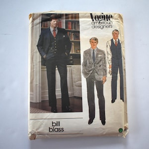May include: A vintage Vogue American Designers sewing pattern featuring a Bill Blass design. The pattern shows illustrations of men's suits in various styles. The cover is cream-colored with text and images.