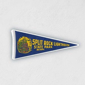 May include: A blue pennant with white trim featuring a vintage illustration of Split Rock Lighthouse and the text "SPLIT ROCK LIGHTHOUSE STATE PARK MINN."