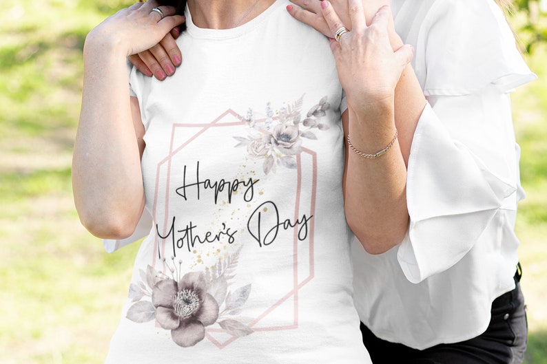 Op de afbeelding: Wit T-shirt met een roze geometrisch frame en een bloemenontwerp. De tekst "Happy Mother's Day" staat binnen het frame.