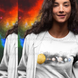 May include: A white t-shirt featuring a graphic of the solar system, with a yellow sun and planets in shades of blue, brown, and orange. The planets are arranged in a line, with the sun on the left and the planets extending to the right. The graphic is set against a black background.