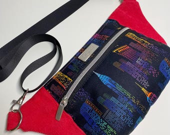 Könnte beinhalten: Eine rote und schwarze Bauchtasche mit einem Stadtbild-Druck und einem silbernen Reißverschluss. Die Tasche hat einen schwarzen verstellbaren Gurt mit einem silbernen Clip.