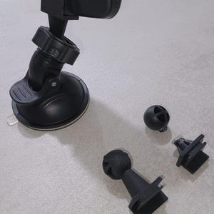 Puede incluir: DVR de coche negro con soporte de ventosa y accesorios de montaje adicionales. El DVR está etiquetado como "FULL HD CAR DVR 1080P". Los accesorios incluyen una rótula y dos clips de montaje.