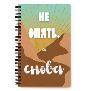 May include: A spiral bound notebook with a brown and beige desert landscape design. The text "НЕ ОПЯТЬ, а СНОВА" is printed in white on the cover.