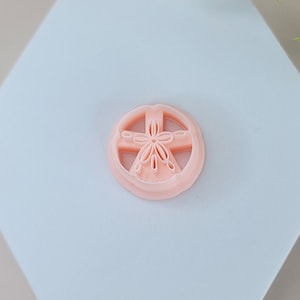 May include: A light pink sand dollar shaped silicone mould on a white hexagonal surface.