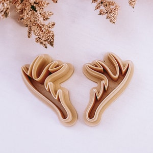 May include: Two brown plastic cookie cutters shaped like reindeer antlers.