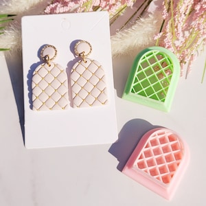 May include: Two pairs of pink and gold earrings with a quilted design. The earrings are displayed on a white card with two pink and green plastic molds.
